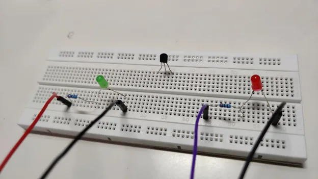 Breadboard with a temperature sensor and green and red LEDs wired with jumper cables