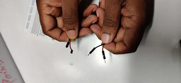 Hands holding two jumper wires with male and female ends
